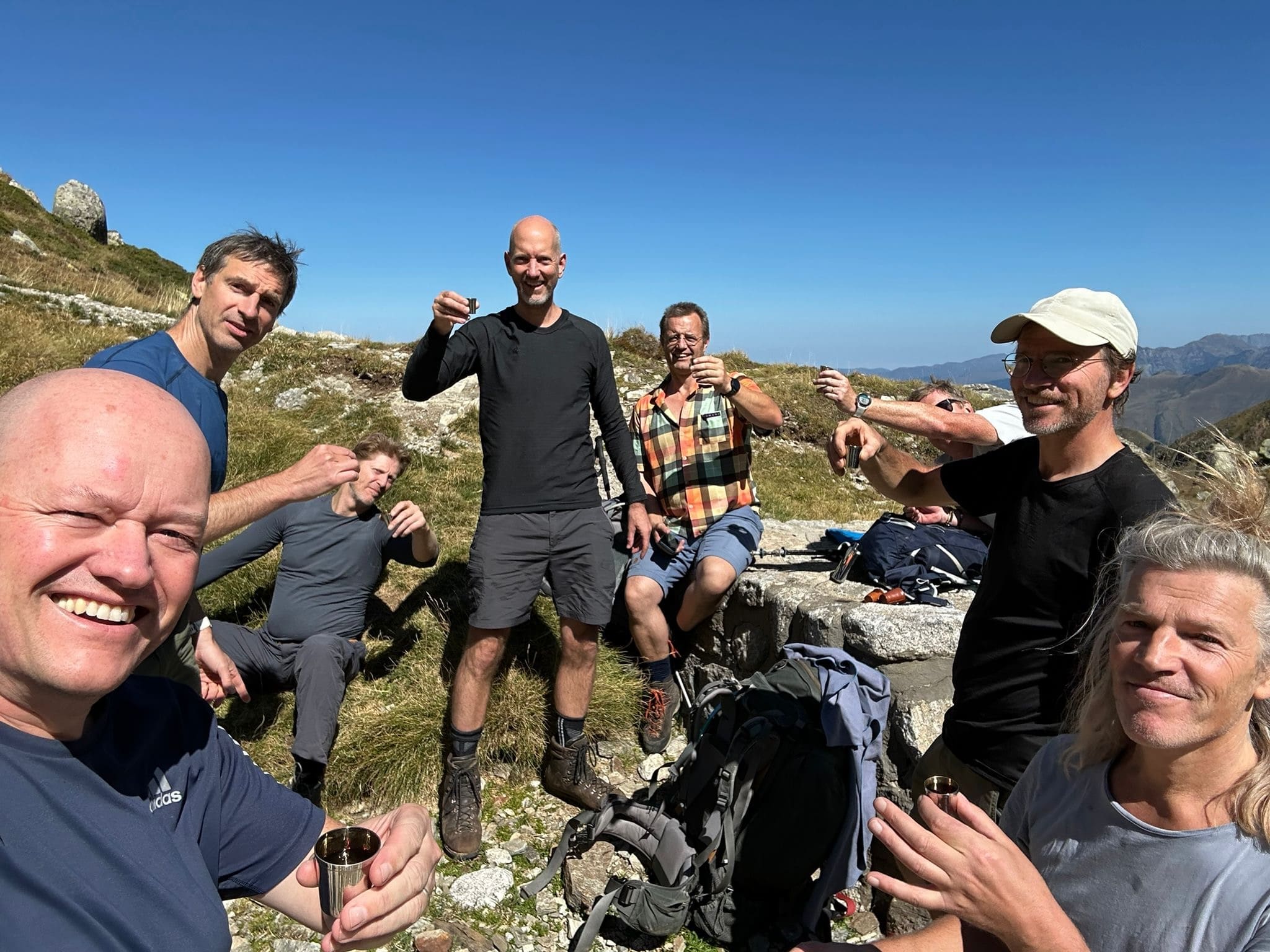 Vriendengroep proost met kleine bekertjes tijdens een bergwandeling in de Pyreneeën
